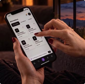 A phone showing One Raven scenes — Good Morning, Good Night, Movie Time, Goodbye — held in both hands.