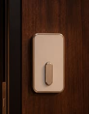 The interior side of a smart deadbolt in a warmly lit entry.